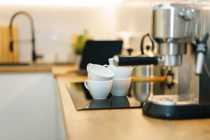 White coffee cups beside espresso machine on counter.