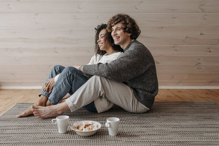 Smiling couple sits together on woven carpet