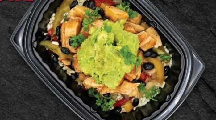 Chicken enchilada bowl with seasoned chicken, black beans, peppers, rice, and guacamole in a takeout container.