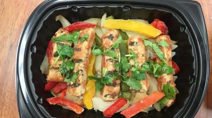 High-protein meal of grilled chicken fajita strips with bell peppers, onions, and cilantro in a Clean Eatz Kitchen container.