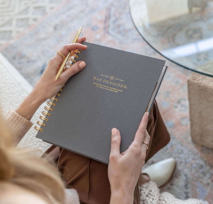 how to plan, woman holding day designer planner, closed charcoal gray book