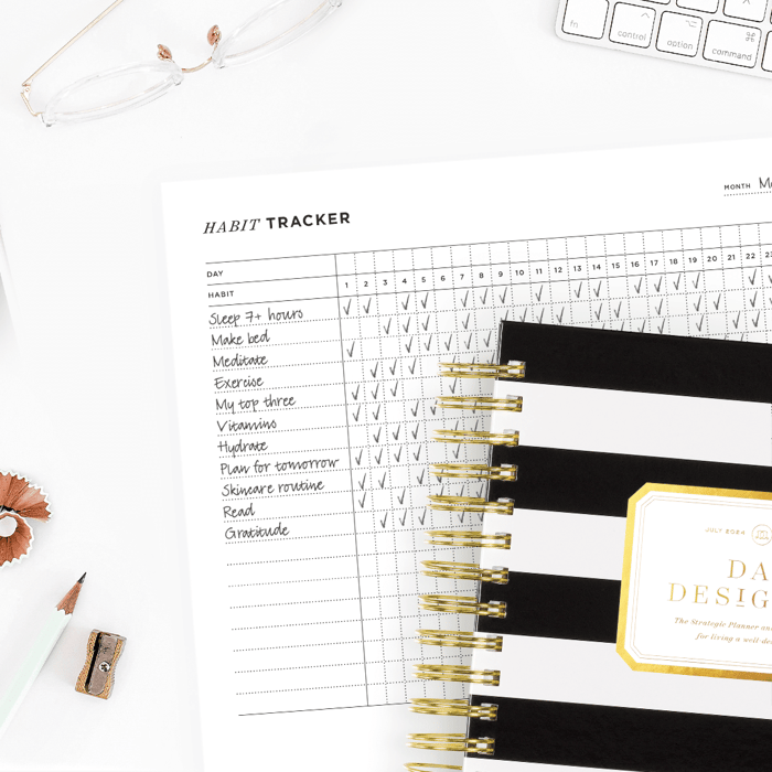 habit tracker free printable filled in to show usage, underneath a black and white striped day designer planner