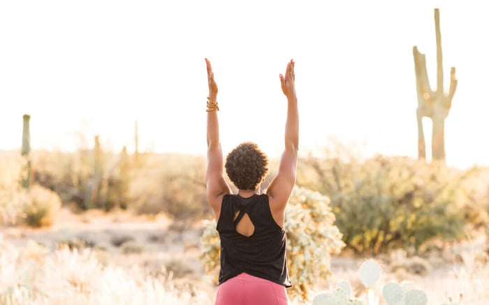 Simple Wellness Rituals, woman practicing wellness by stretching arms, outdoor background with cactus, sage brush