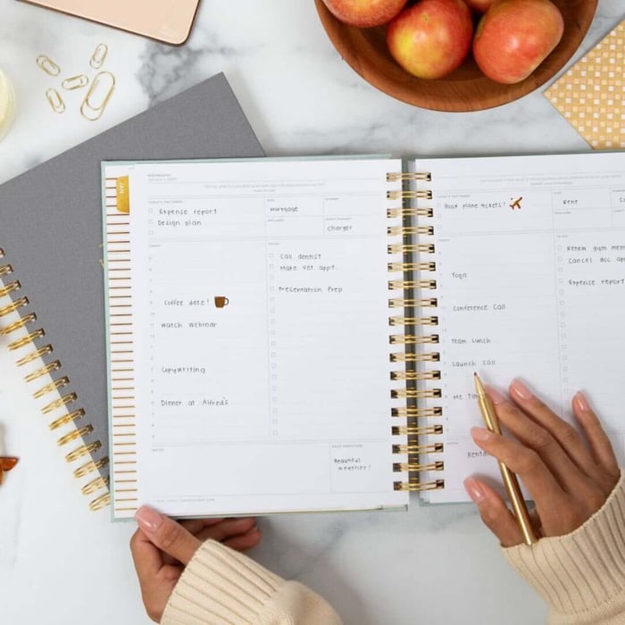 day designer holiday survival guide, written on planner page, open book, desk