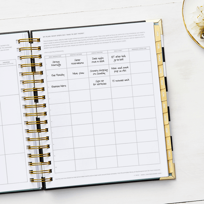 monthly actions written on open planner showing goal pages