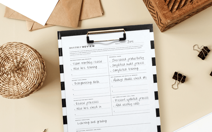 monthly reflection printable written on page, black and white striped clipfolio, beige background, basket, paperclip, stationery, box