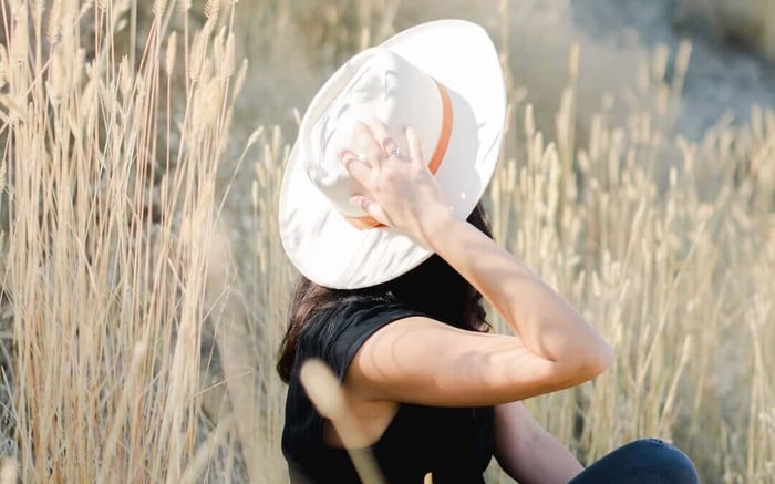 rewire your brain for happiness, woman sitting outdoors, holding hat on head