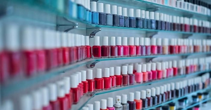 A close-up of a beauty nail shop shelf interior. There's a wide array of nail polish colors, ranging from pink to purple.