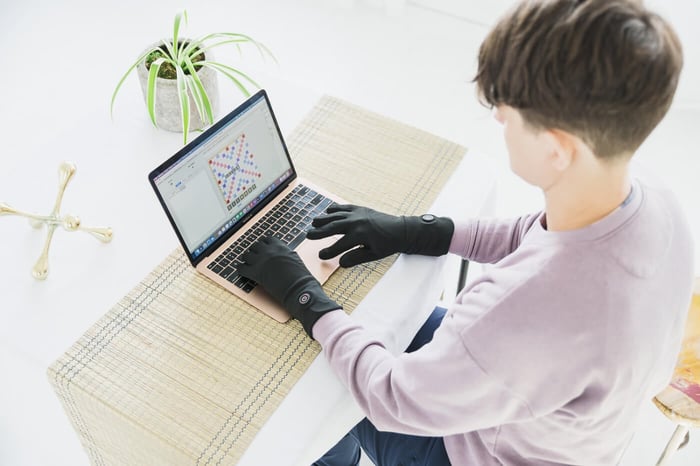 Founder Natalie typing at her computer wearing Toasty Touch heated Raynaud's gloves.