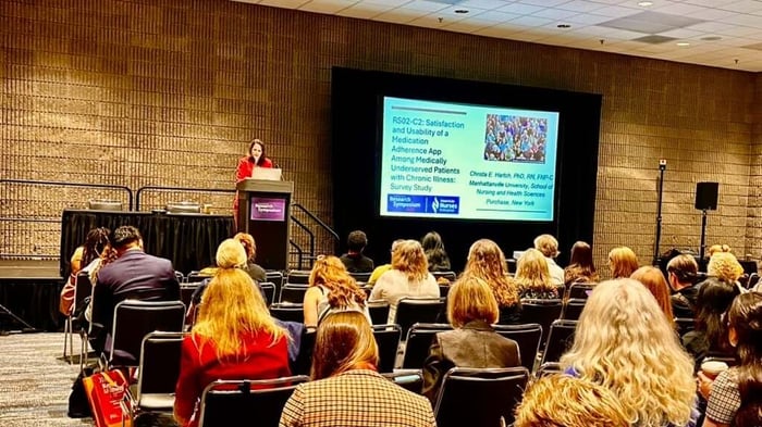 Presenter speaking at podium with big screen in front of audience