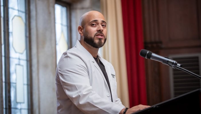 Nursing Student Irving Escobar giving his speech in white nurse's coat