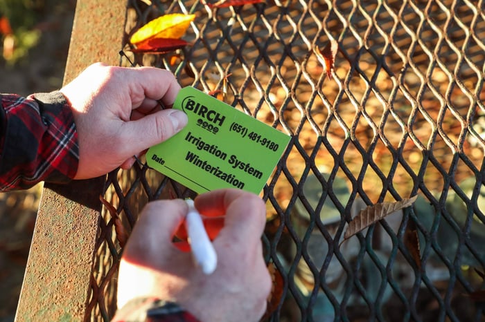 man hovering pen over irrigation system winterization tag