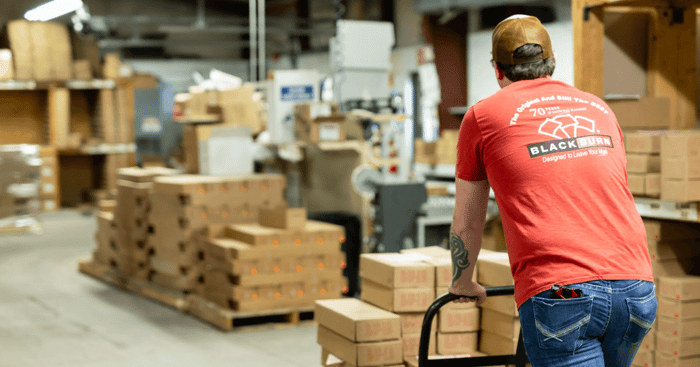 Blackburn employee pushing boxes in warehouse