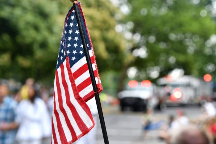 miniature American flag waving in front of celebration in busy street
