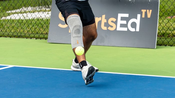 Close up shot of a pickleball mid air and a player behind it