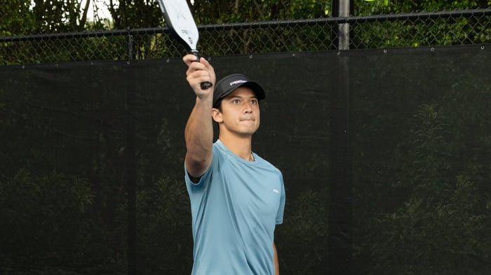 Man with arm raised up holding a pickleball racket
