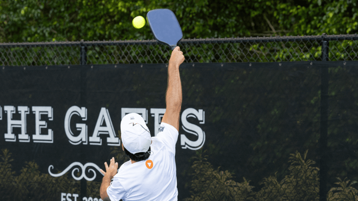 Player jumping to hit a pickleball