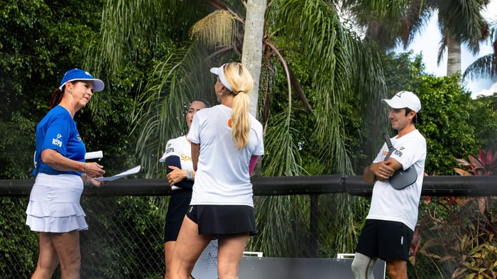 Group of four pickleball players discussing game strategies