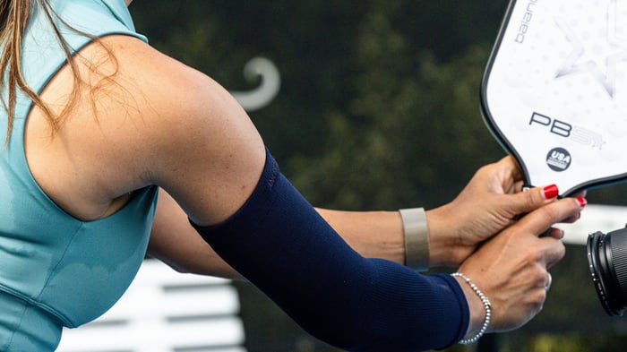 Close up shot of woman's arm holding pickleball racket
