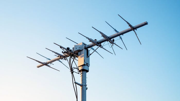 Professional Yagi directional antenna mounted on a steel pole outdoors, showing the boom, reflector, and multiple director elements against a blue sky.