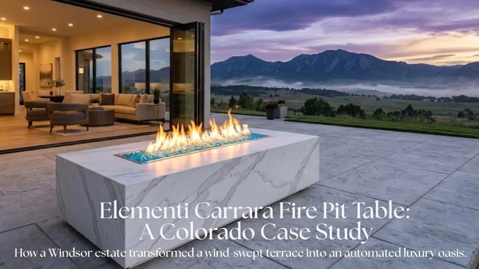 The Elementi Carrara Fire Pit Table with Bianco White marble porcelain finish and glowing flame on a luxury stone patio in Windsor, Colorado at sunset.