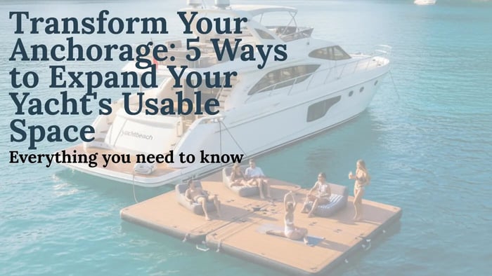 A luxury yacht anchored in a beautiful turquoise cove with a Yachtbeach inflatable platform deployed next to it, featuring several people relaxing, doing yoga, and socializing on the platform. The image shows a serene, expanded outdoor living space