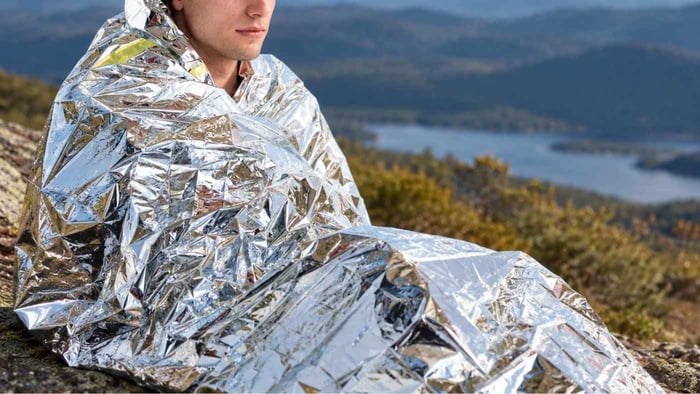 person wearing emergency thermal blanket