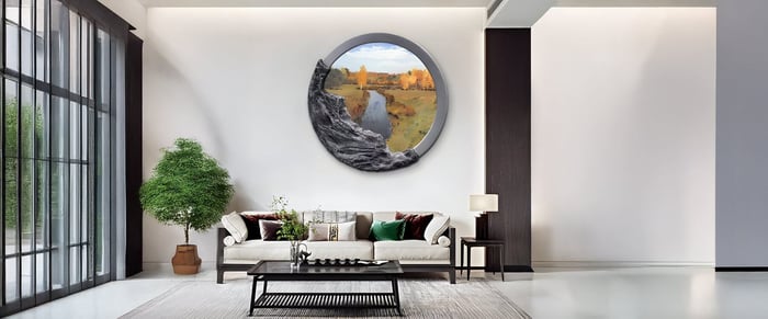 A contemporary living room features a striking round canvas art piece depicting a canyon landscape with golden hills and a cascading waterfall, framed in soft metallic hues.