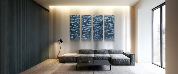Modern living room with triptych blue wave-textured wall panels and a sleek low-profile gray sofa.