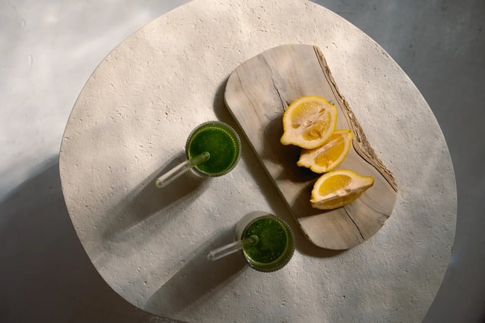 Benefits of green juice are exemplified by showing lemon wedges alongside two frothy cups of green juice