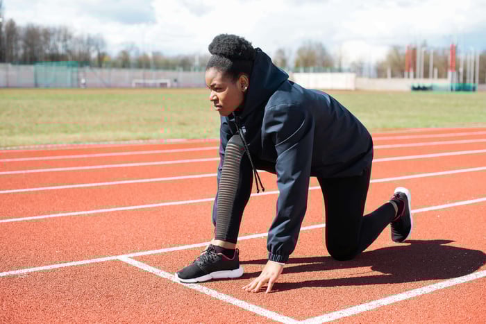 A woman on a track who is prepared to begin a race, she is alone.  This is a metaphor for her beginning her healthy journey by improving daily habits and making changes in her life.
