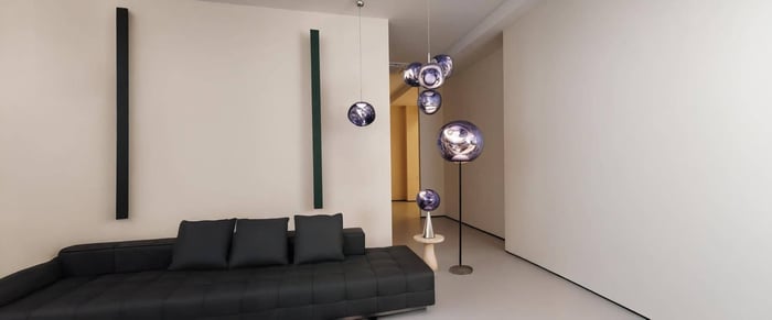 Modern minimalist living room with black sofa and cluster of sculptural pendant lights.