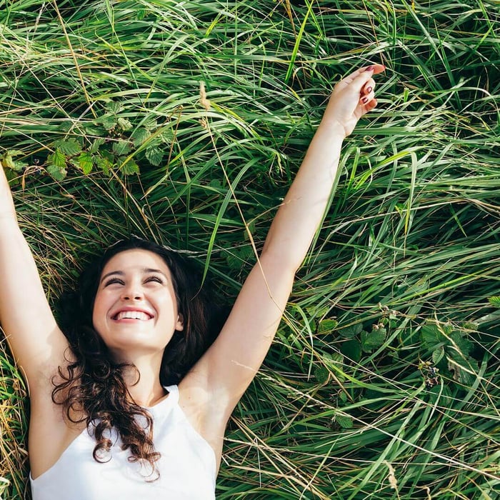 why your bedding causes night sweats — woman relaxing on natural grass after cooler, deeper sleep with breathable bedding