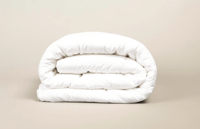 Wool vs bamboo duvets comparison – folded white wool comforter on neutral background showing natural breathable bedding materials