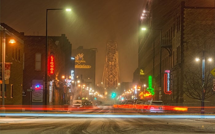 Winter driving in Minnesota. Driving in a snowstorm in Downtown Duluth, with glowing neon signs, and the Aerial Lift Bridge visible in the distance.