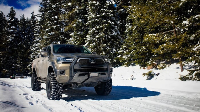 Pickup trucks driving through a forest on Minnesota roads on a snowy day, representing the Minnesota truck market