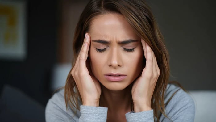Woman with closed eyes holding temples in discomfort