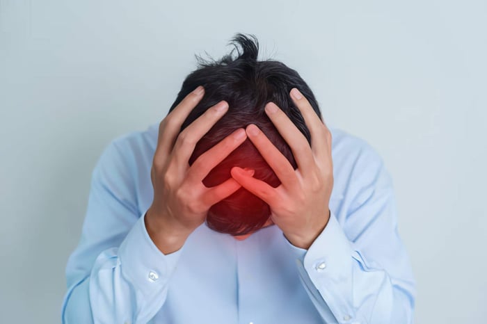 Man holding head with red highlighted pain area