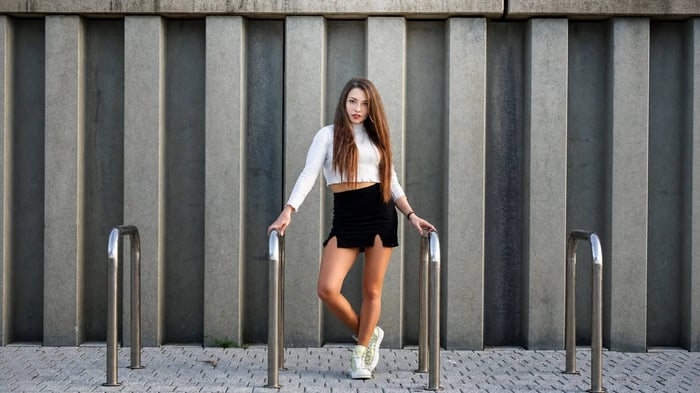 Confident young woman in an edgy urban setting wearing a black crop top layered under a two-tone leather jacket. A winter-ready fashion look that proves crop tops can work year-round
