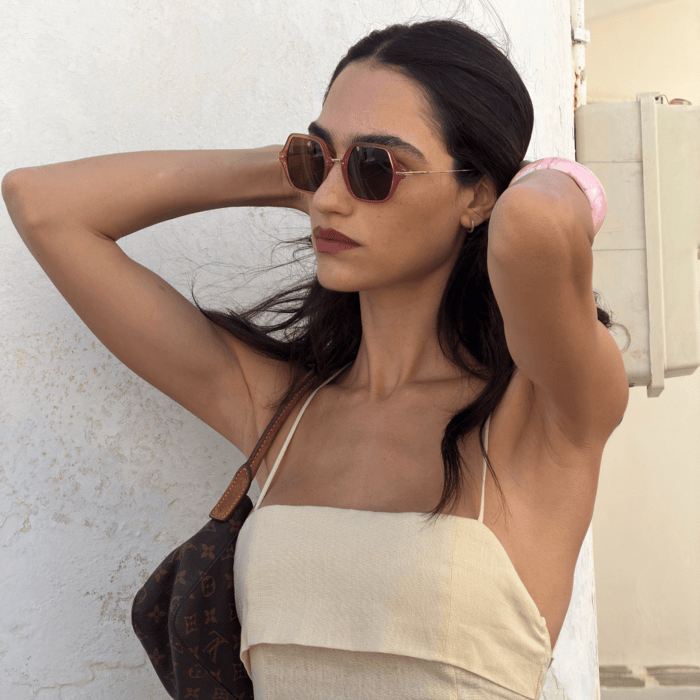 Circular luxury investment piece, woman wearing ANEA HILL Portofino sunglasses in deep burgundy Italian cellulose acetate with gold hardware and a Louis Vuitton bag