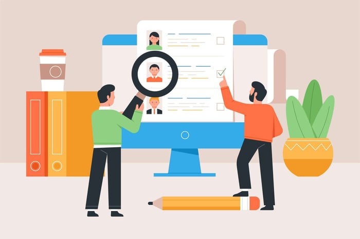 A recruiter and a hiring manager collaborating on how to write a job description on a laptop