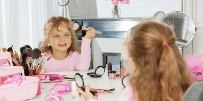 Niña usando un kit de brochas para maquillaje durante un juego creativo supervisado