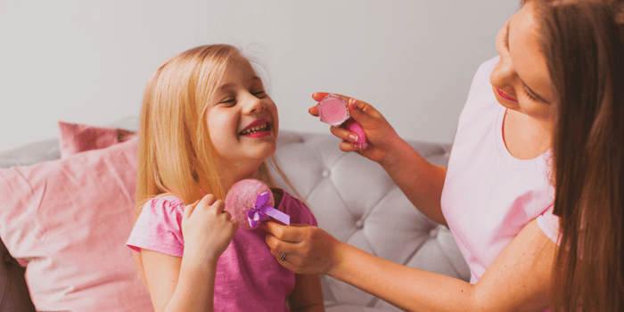 Madre e hija usando un kit de maquillaje para niñas durante un juego creativo en casa