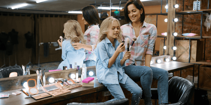 Madre e hija explorando maquillaje para niñas durante un juego creativo en casa