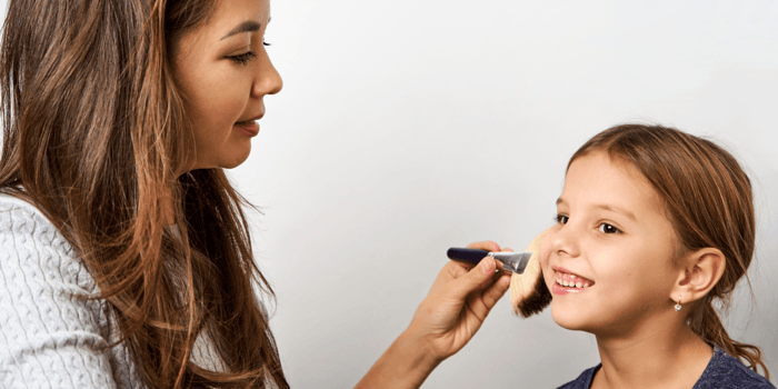 Mom applying daughter makeup. Why natural makeup? A parent’s guide to safer, age-appropriate beauty play
