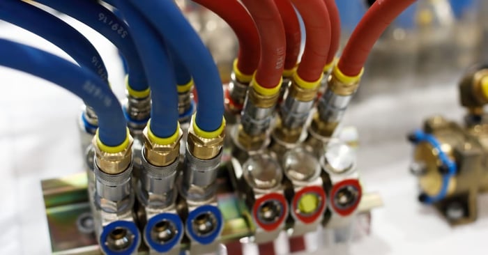 Blue and red pneumatic hoses connect to metal air fittings on a manifold, with yellow collars securing each line.