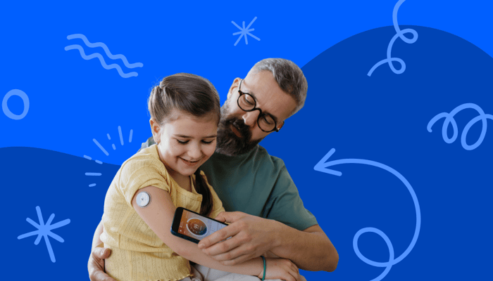a child wearing a blood glucose monitor with her father measuring the reading