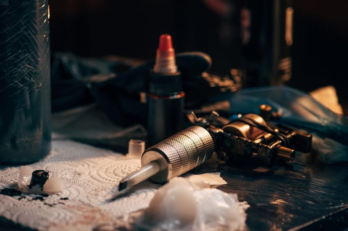 Professional tattoo machine and sterile needle cartridges on workstation, highlighting the importance of verified tattoo equipment and supply chain tattoo needle safety