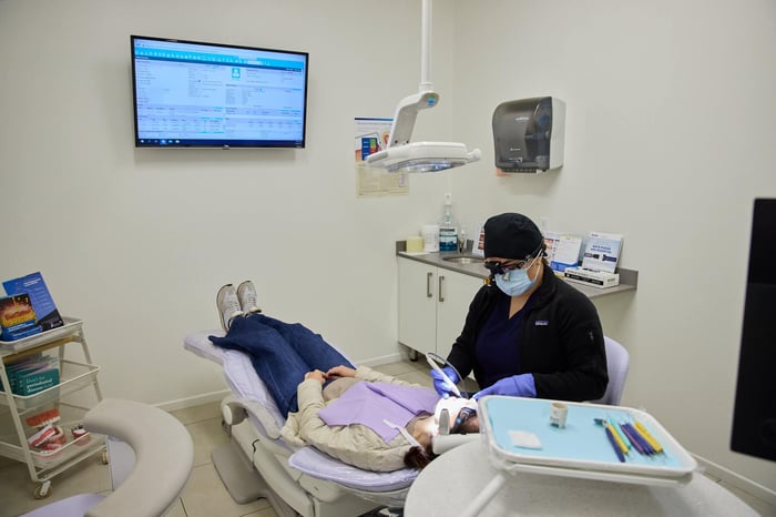 A dentist wearing a black robe talking to a patient