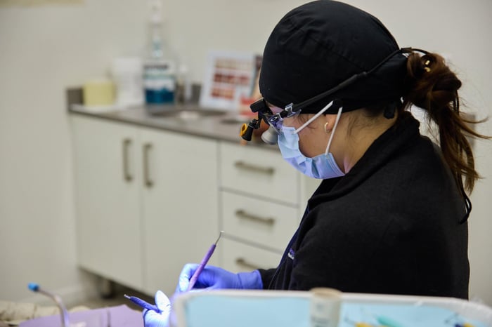 A woman wearing a black scrub and a face mask